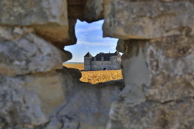 The Clos de Vougeot's château seen through a gap in an old stone wall