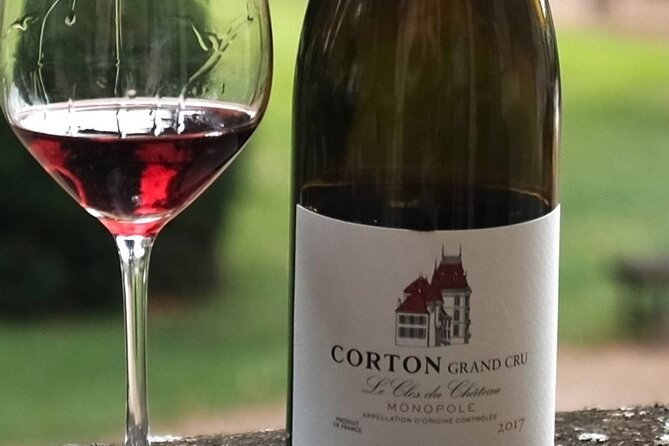 A bottle of Corton Grand Cru beside a glass of red wine