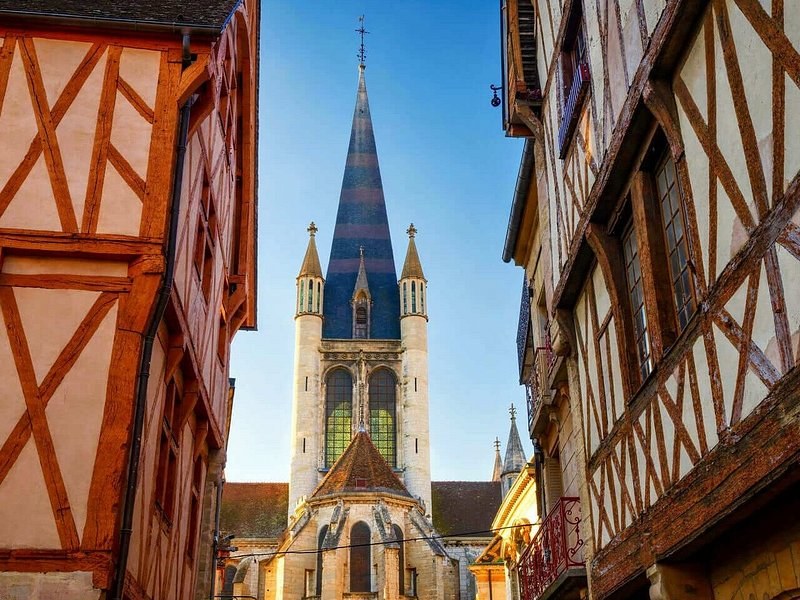 Half-timbered houses framing a church tower and its striped spire