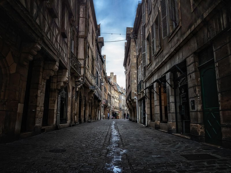 A narrow old-town street of stone houses, its paving wet after rain